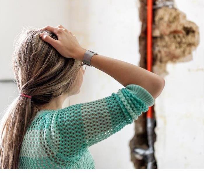 a person in distress looking at a wall where water damage has occurred