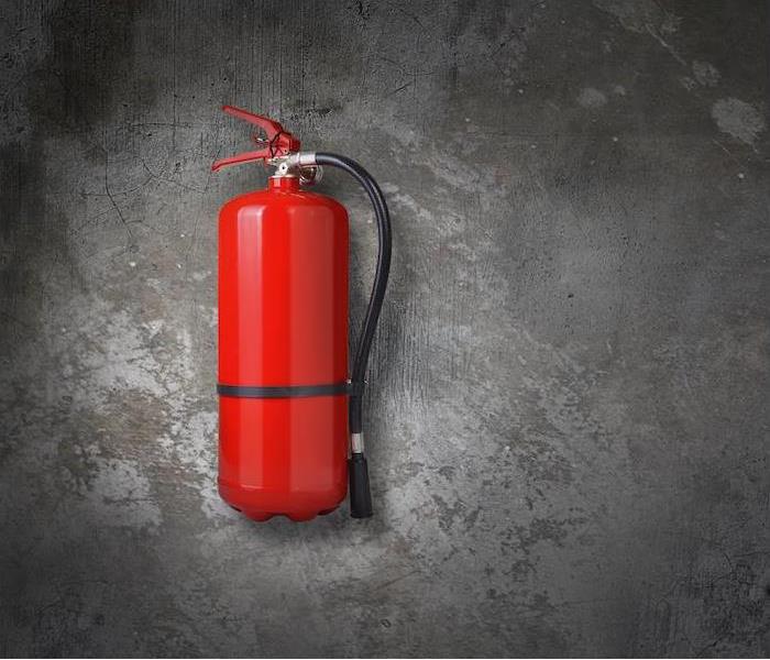 a red fire extinguisher hanging on gray concrete wall